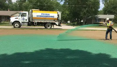 Hydroseeder truck spraying green slurry on lawn in Peoria IL by Chop Chop Landscaping